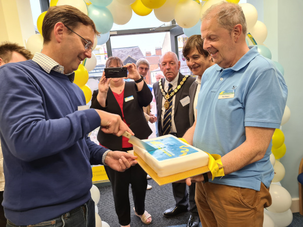 Darren cutting the cake inside the TaxAssist Accountants shop